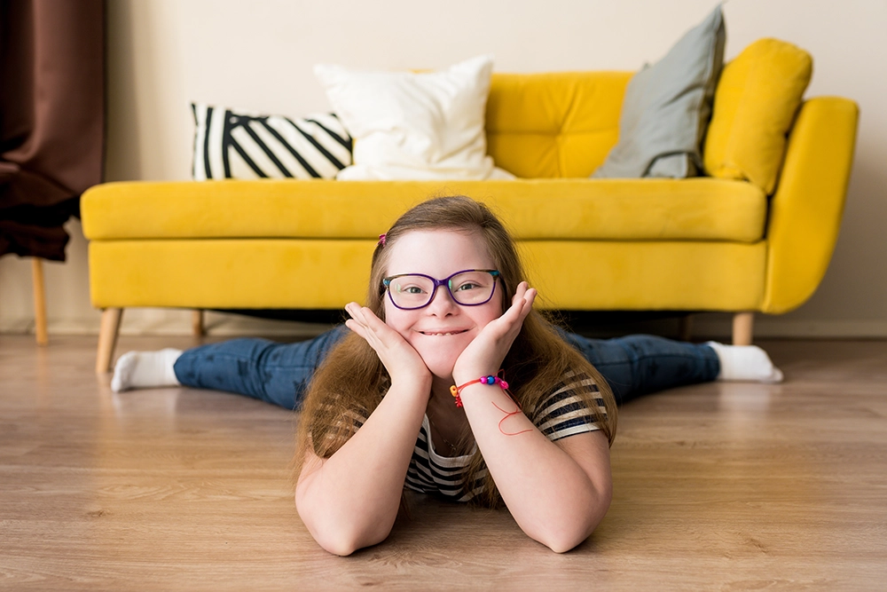 teen girl with Down Syndrome smiling while laying on the floor.
