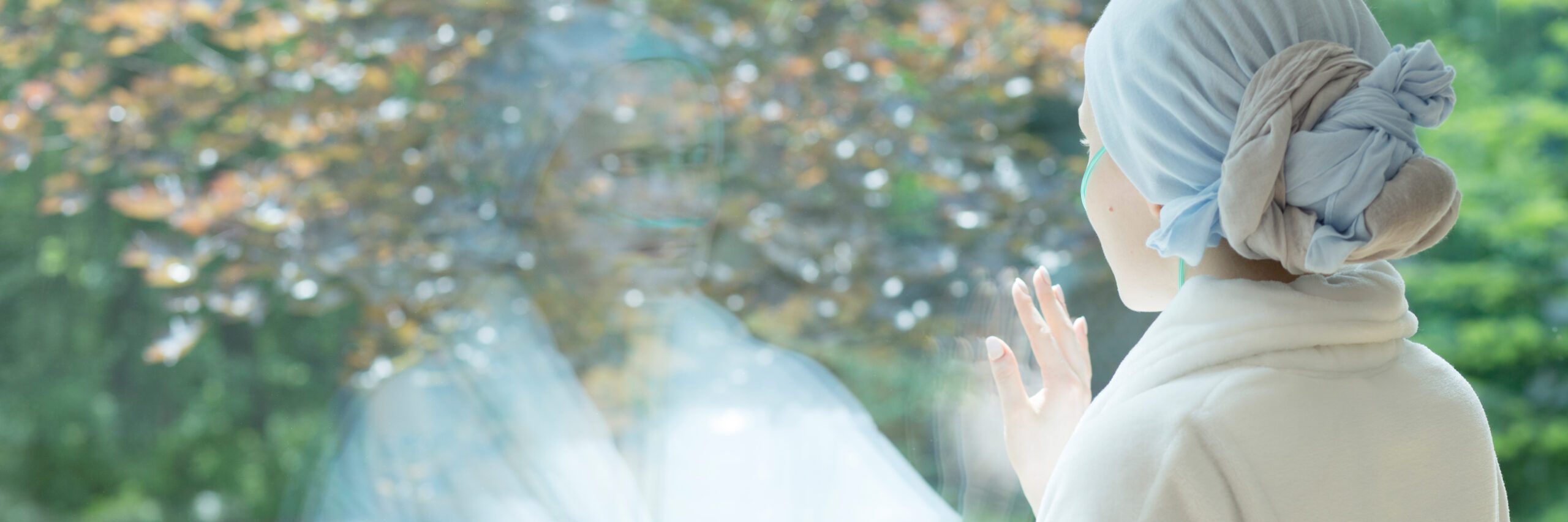 Panorama of sick woman with cancer touching window in the hospice during treatment