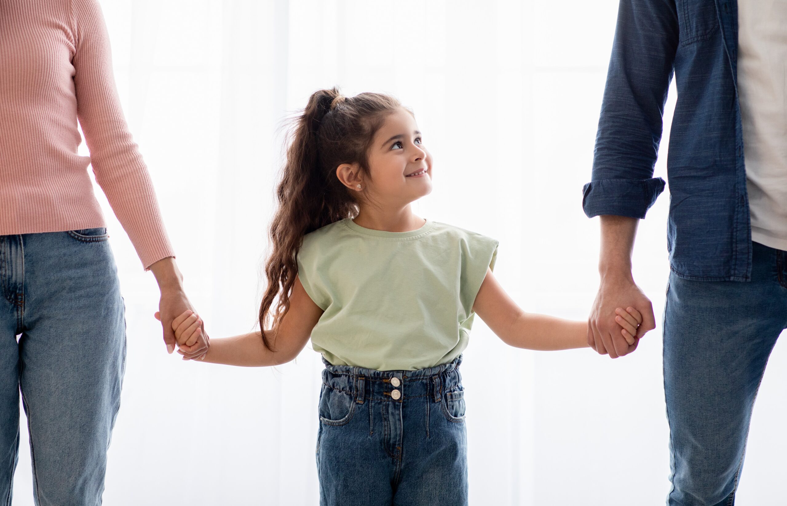 Girl holding hands with parents