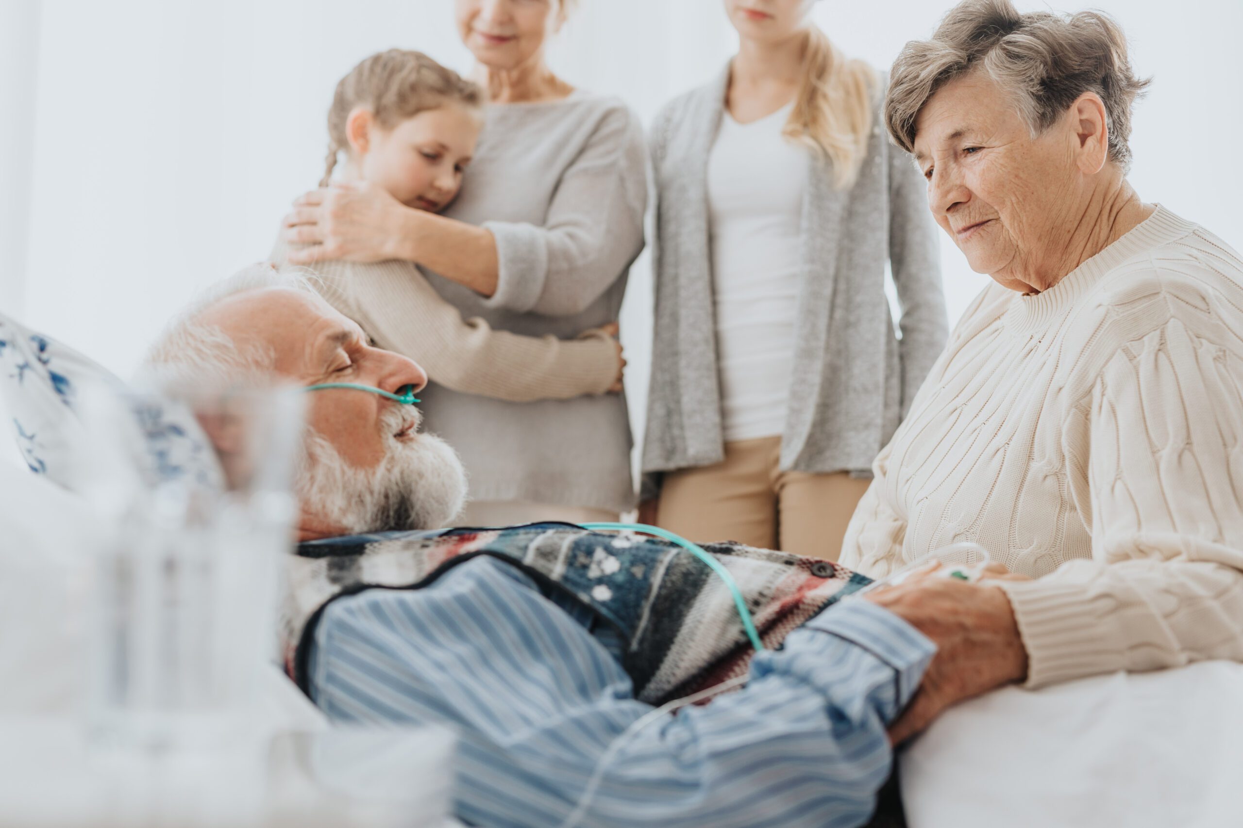 Older man dying in a hospital surrounded by family