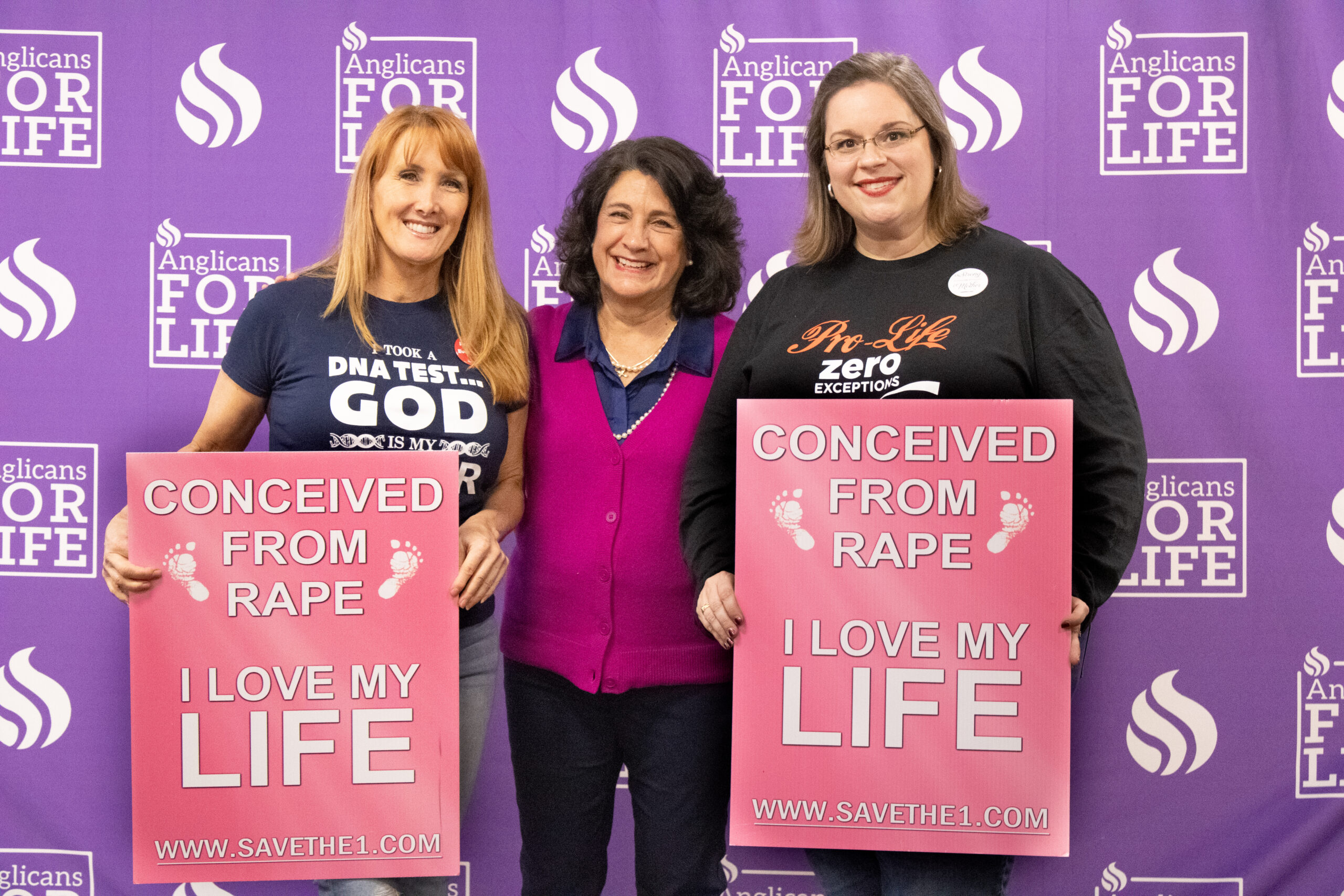 Women holding "conceived from rape" signs at an event