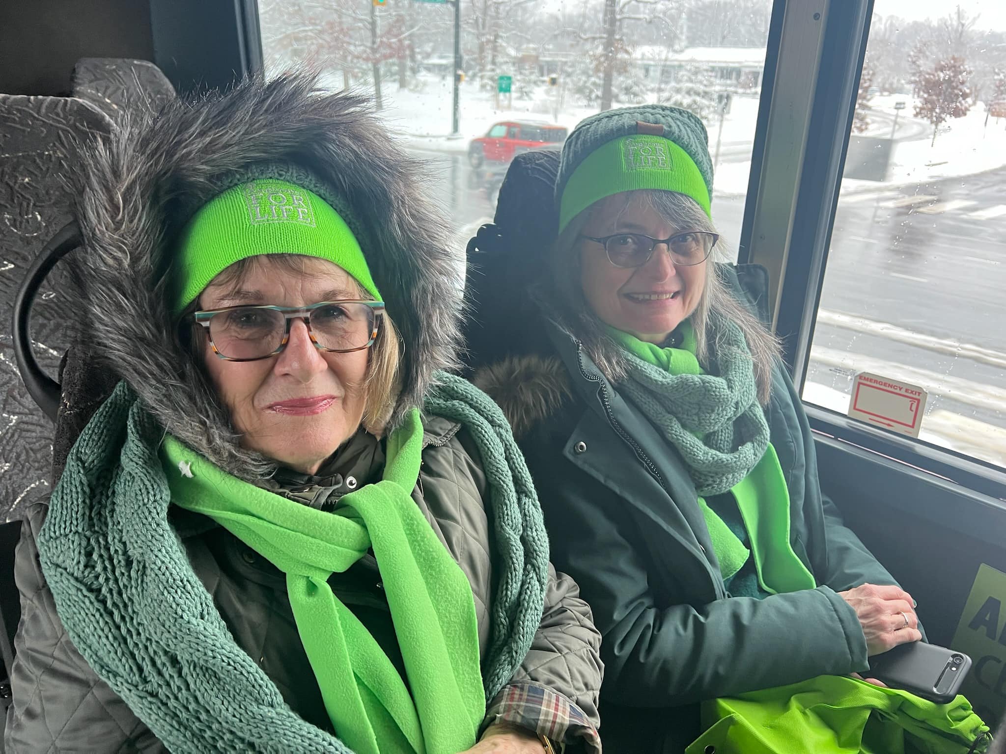 People on a bus with lime green hats and scarfs